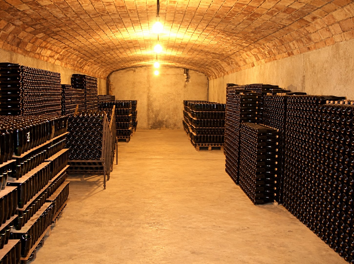 Piles d'ampolles de cava criant a sota terra, a la volta de maó del celler